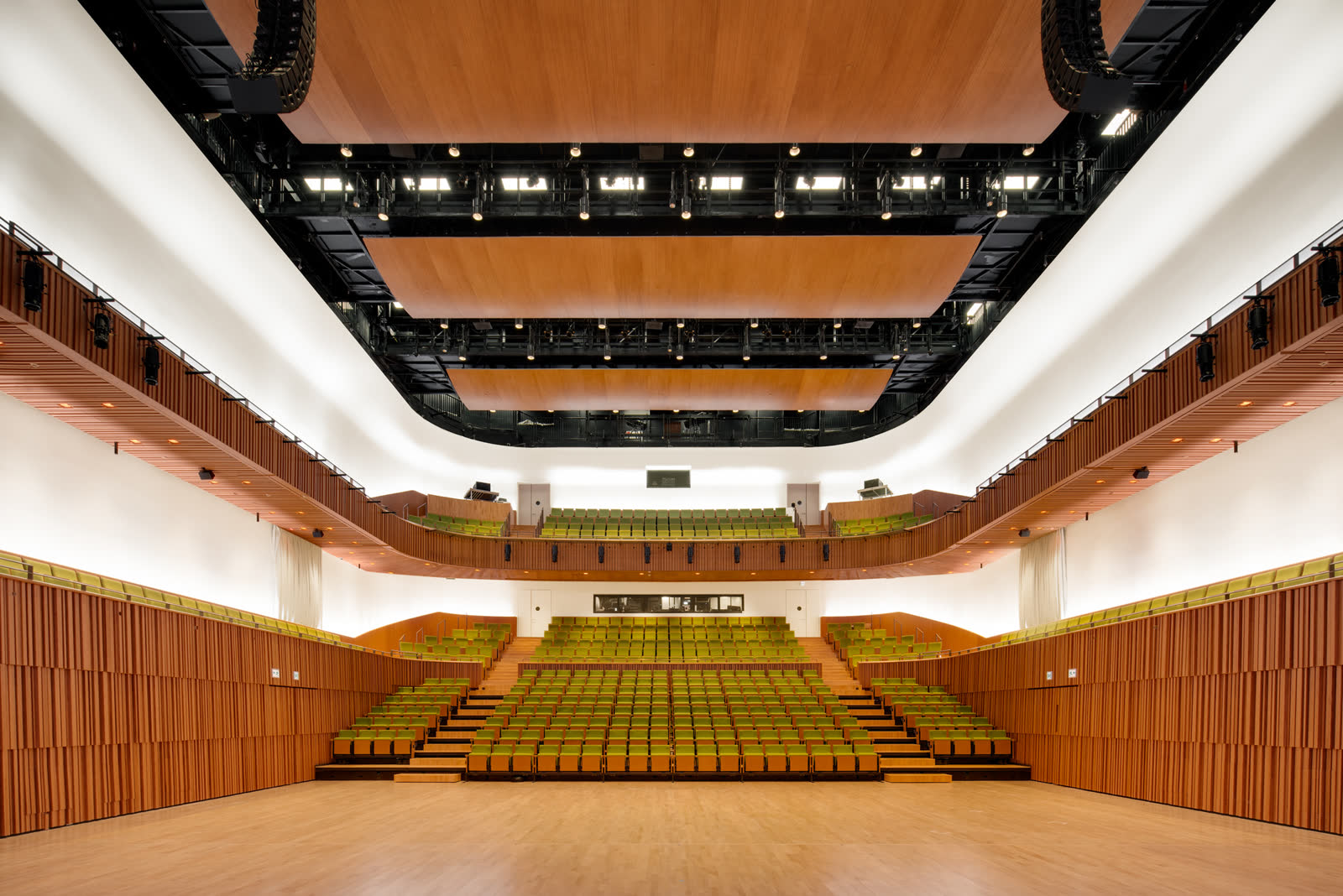 طراحی سالن اجتماعات؛ تالار Shaw Auditorium با صندلی‌های پلکانی، بالکن و سقف چوبی آکوستیک