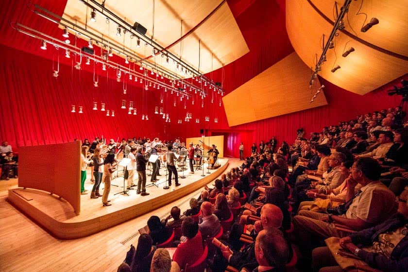 سن و مخاطبان در تالار Auditoriumdelparco در L'Aquila با پرده قرمز و پنل‌های چوبی بازتابنده